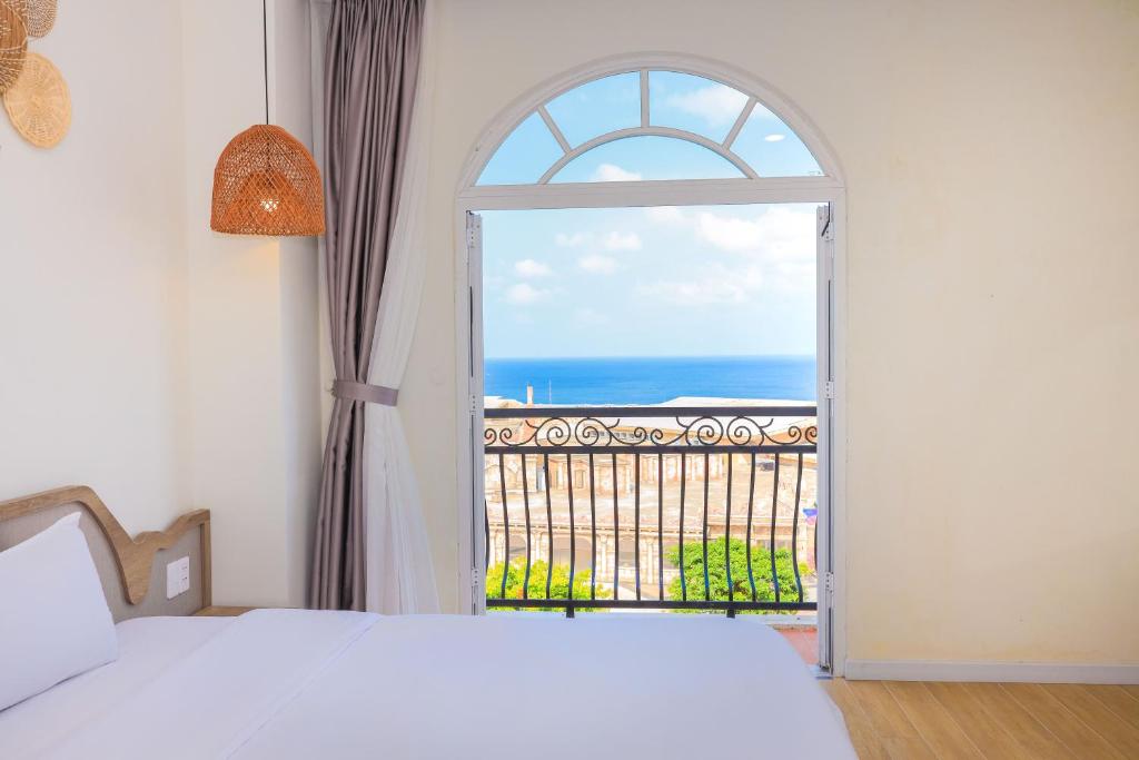 een slaapkamer met een raam en uitzicht op de oceaan bij Lily House Hotel Phu Quoc in Phu Quoc