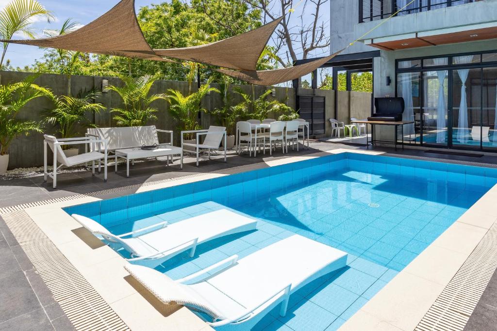 een buitenzwembad met stoelen en een tafel bij ISLA VILLA 2 Luxury Pool Villa near beach with karaoke video games barbecue in Maribago