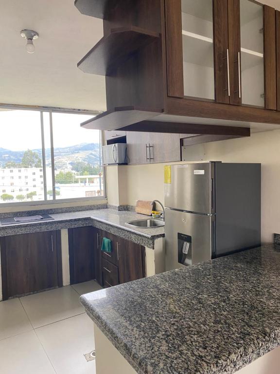 a kitchen with granite counter tops and a refrigerator at Apto. a una cuadra del Terminal in Quito