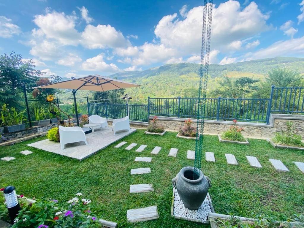 a garden with a patio with an umbrella and chairs at Dream Hills Villa, Nillambe Kandy in Kandy