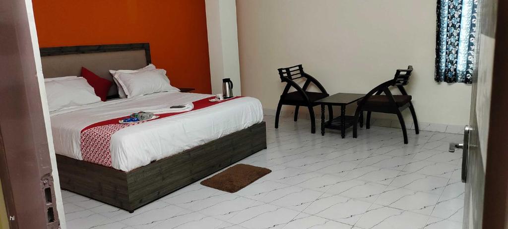 Schlafzimmer mit einem Bett, einem Tisch und Stühlen in der Unterkunft Super OYO Happy Grand Hotel in Vijayawāda