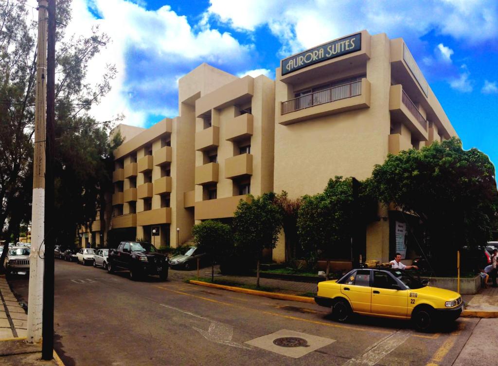 un coche amarillo estacionado frente a un edificio en Aurora Suites, en Guadalajara