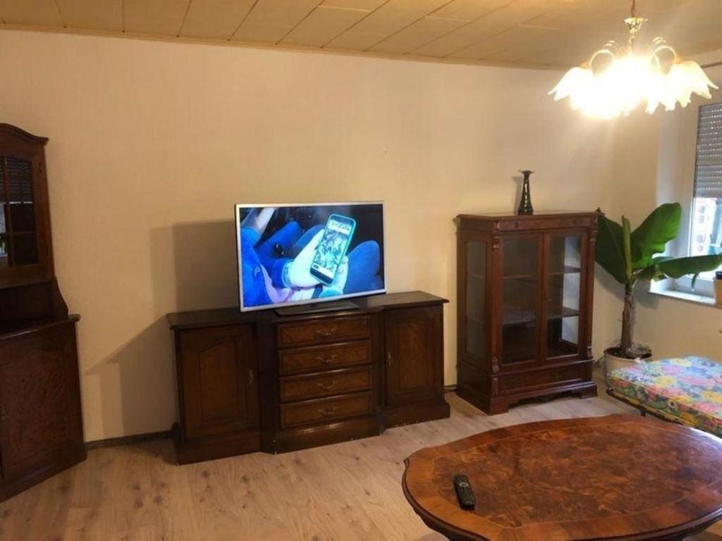una sala de estar con TV de pantalla plana en un armario de madera en 2- Raum Ferienwohnung mit Parkplatz en Weißwasser