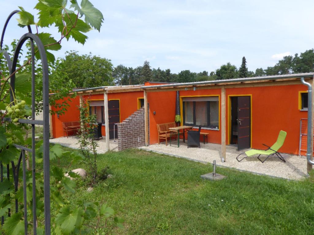 una casa arancione con patio e cortile di Ferienhaus in Kallinchen mit Terrasse, Garten und Grill a Zossen