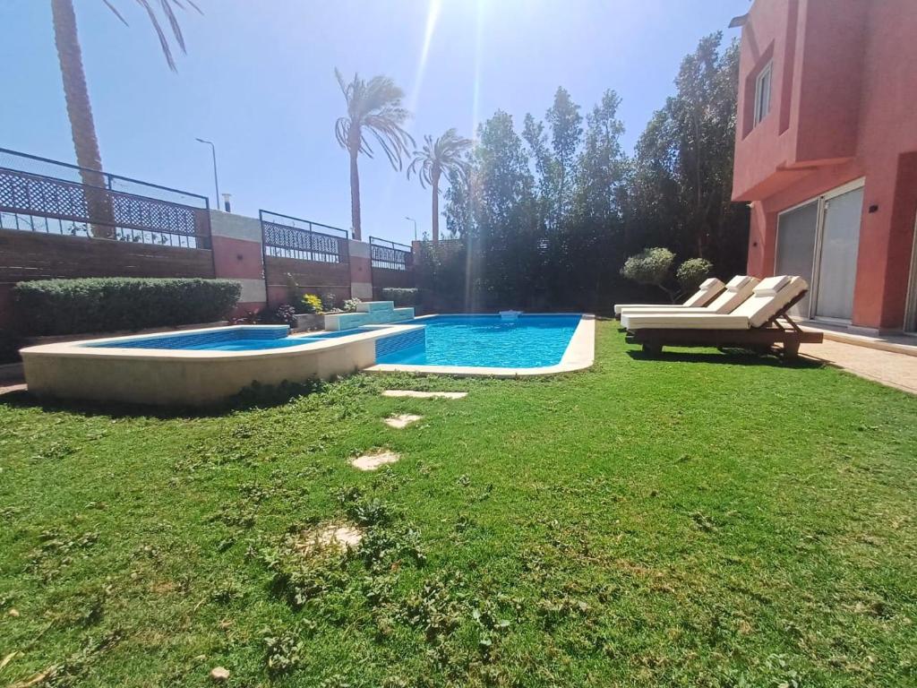 une cour avec une piscine et une pelouse avec des chaises dans l'établissement SHARM el sheikh Villa A7, à Charm el-Cheikh