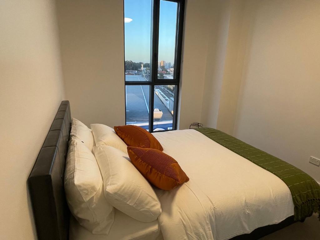a bedroom with a bed with pillows and a window at Stylish Apartment with city view close to beach airport cbd in Sydney