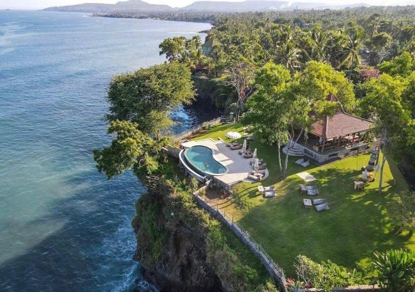 an aerial view of a house on a cliff next to the ocean at Bali Cliff Glamping in Karangasem