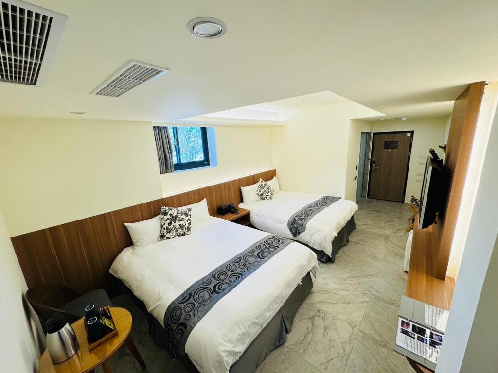 a hotel room with two beds and a television at Dafong Hotel in Zhongzheng