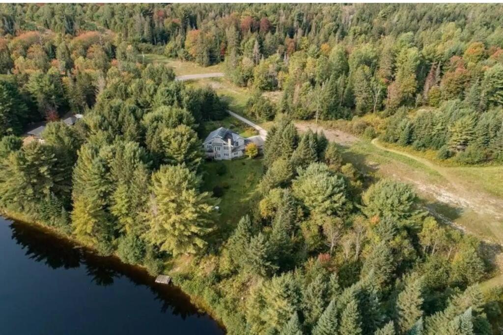 an aerial view of a house in the woods next to a lake at Lovely Muskoka Waterfront Cottage-Hot tub & Sauna! in Bracebridge