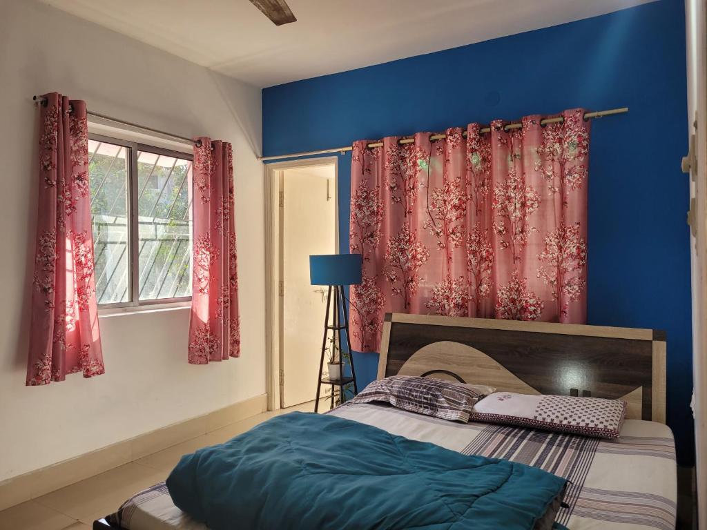 sypialnia z łóżkiem z niebieskimi ścianami i czerwonymi zasłonami w obiekcie Mysa Homestay w mieście Ranchi