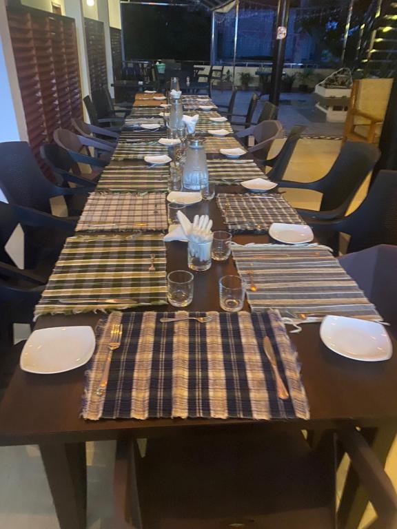 una mesa larga con platos y servilletas. en Guraidhoo Palm Inn, en Guraidhoo