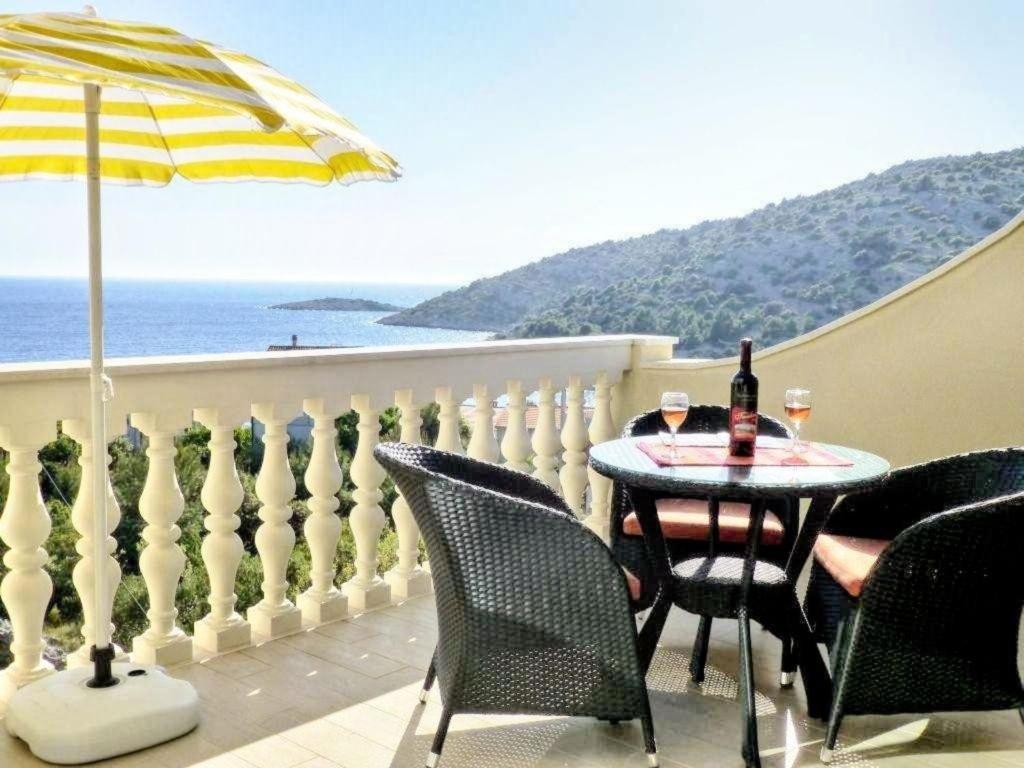 un patio con mesa, sillas y sombrilla en Ferienwohnung für vier Personen mit Hochterrasse und einem herrlichen Meerblick en Ražanj