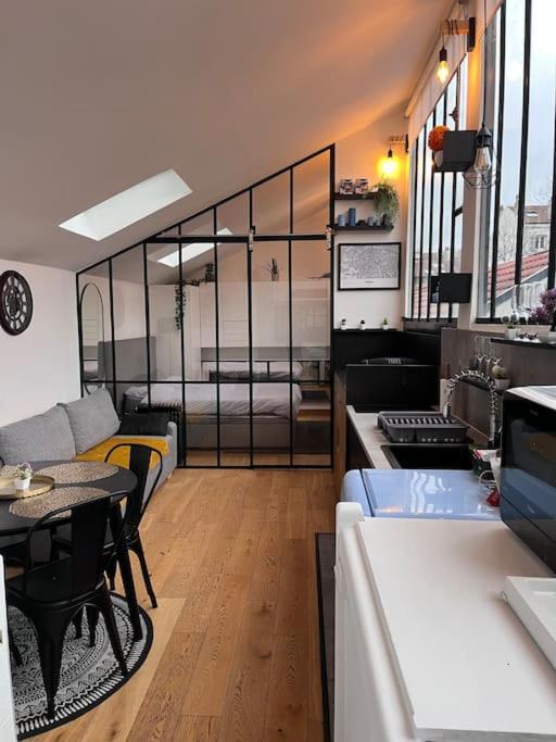 eine Küche und ein Wohnzimmer mit einem Tisch und einem Sofa in der Unterkunft Loft chic climatisé proche château de Vincennes in Montreuil