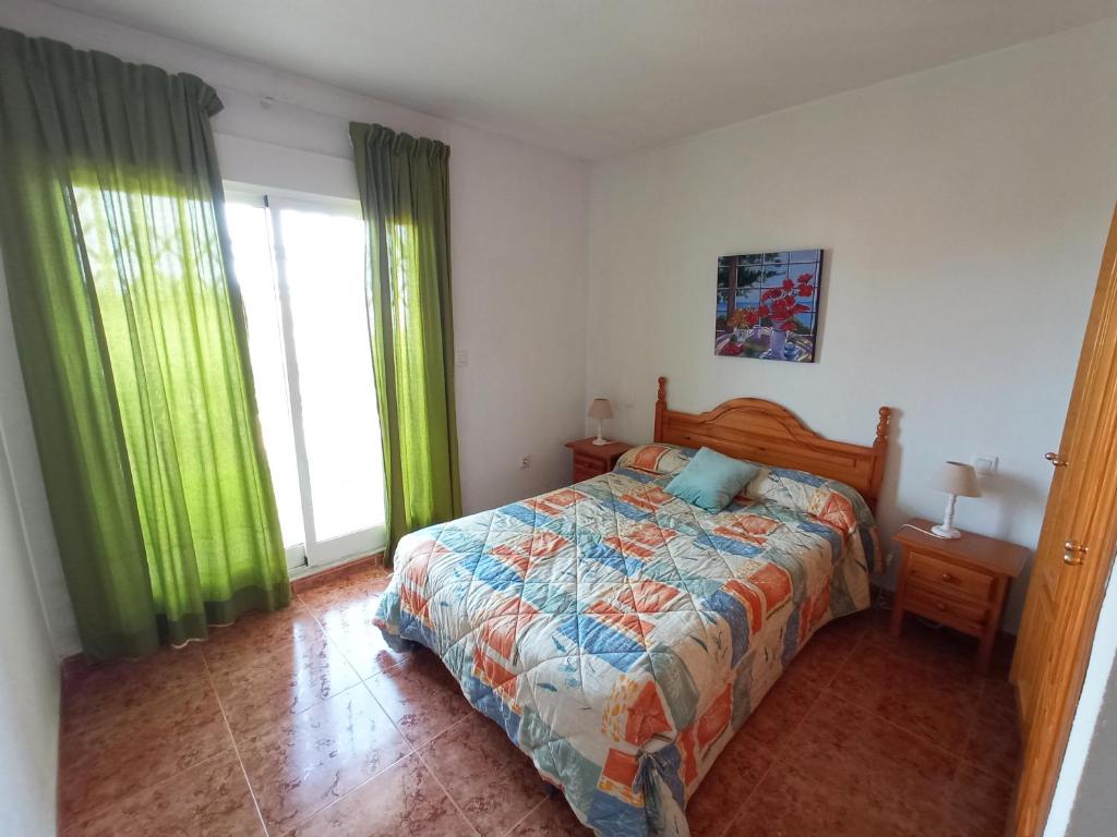 una camera con letto e tende verdi di Adosado con garaje privado - Junto al mar a Los Nietos