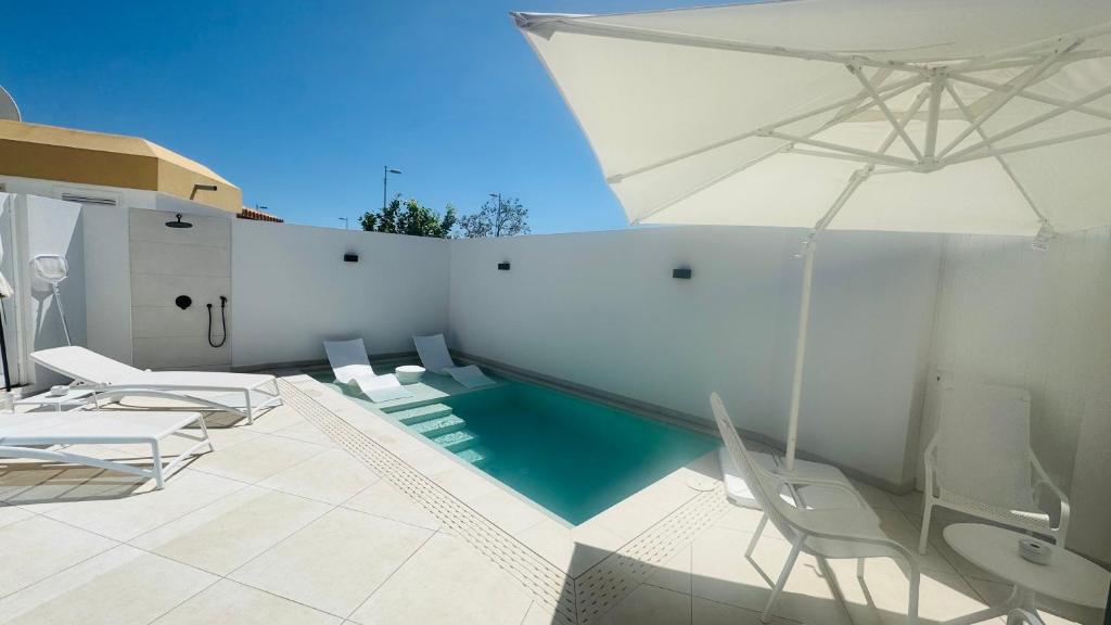 een zwembad met stoelen en een parasol bij Villa Siena, in the center of Playa del Ingles, close to CC Jumbo in Maspalomas