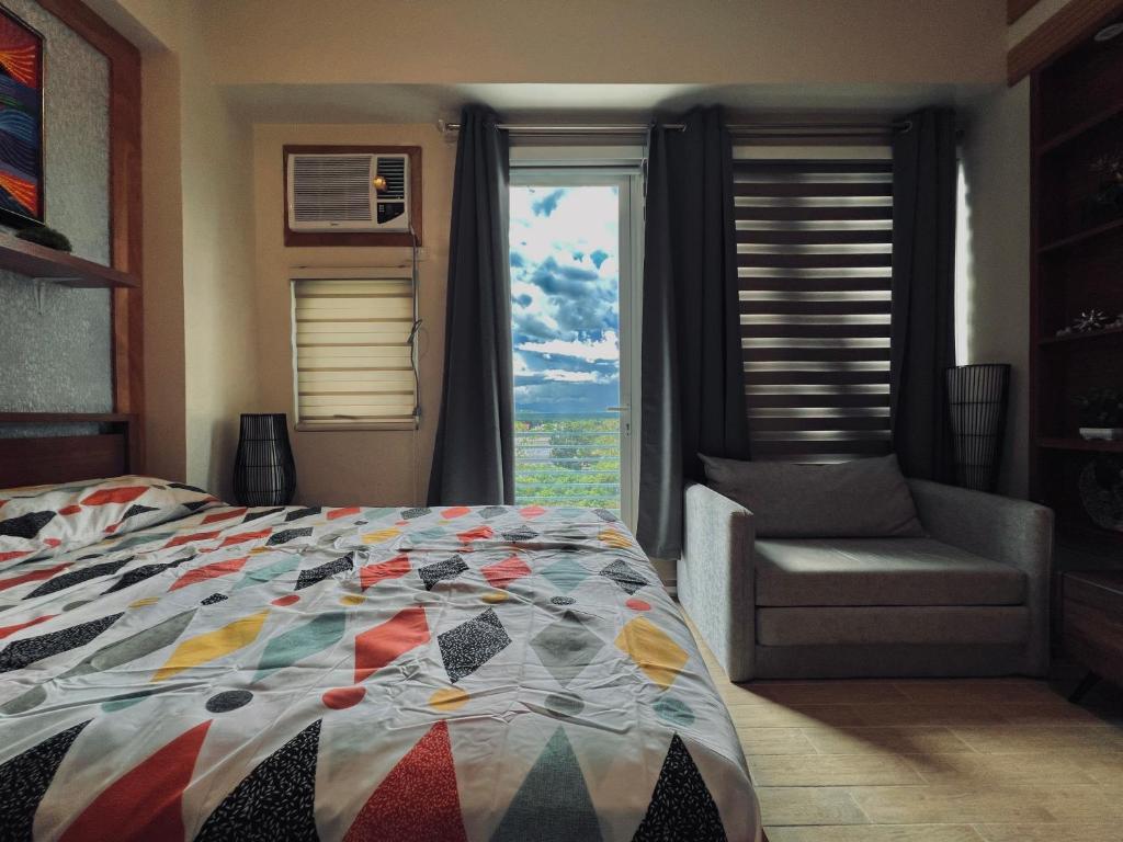 a bedroom with a bed and a chair and a window at 1 Urban Elegance in Iloilo City