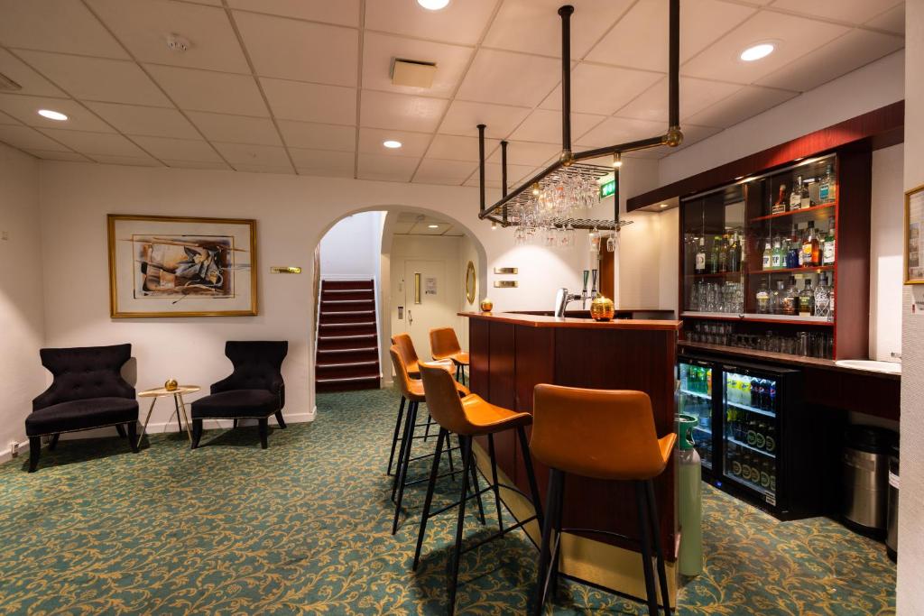 a bar in a restaurant with chairs and a bar counter at Milling Hotel Ansgar in Odense