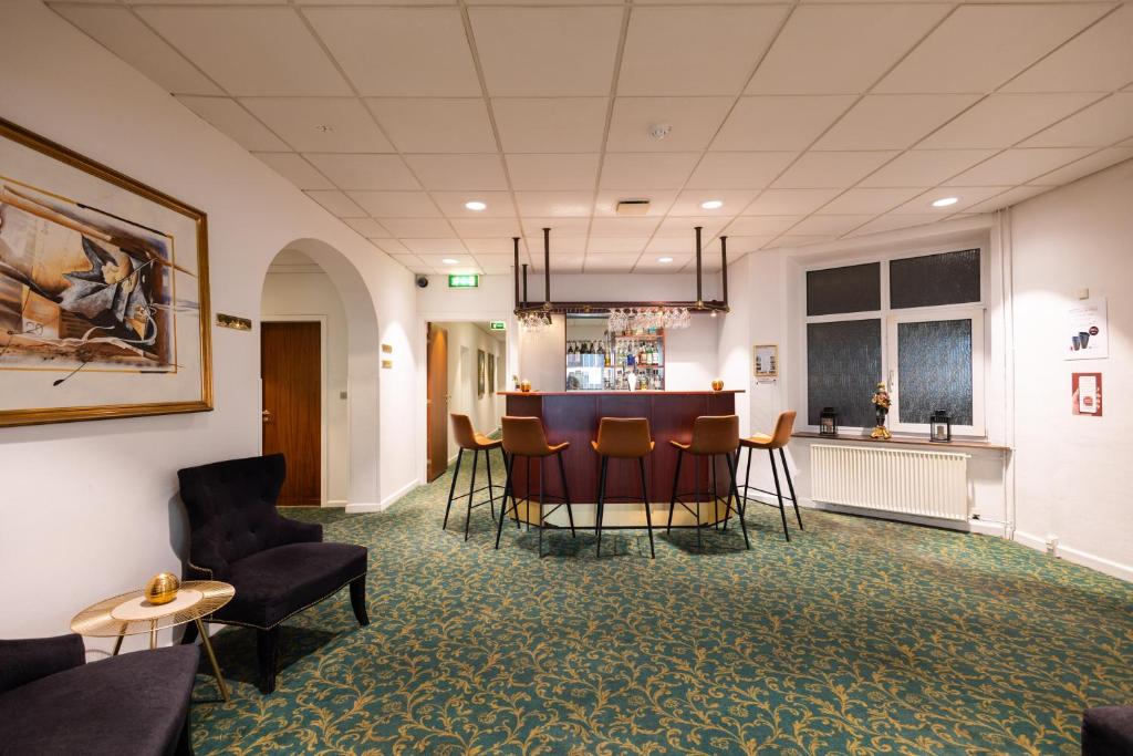 a room with a bar with chairs and a table at Milling Hotel Ansgar in Odense