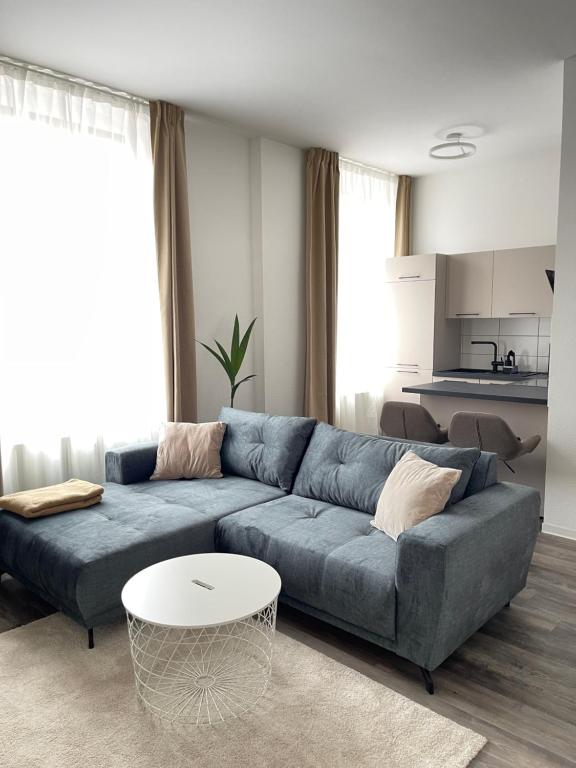 a living room with a blue couch and a table at Moderne und stilvolle Wohnung direkt am Teich in Altenburg