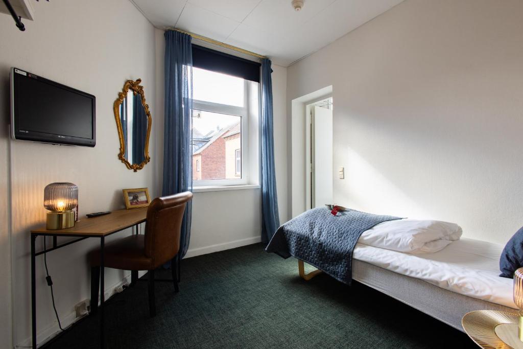 a bedroom with a bed and a desk and a window at Milling Hotel Ansgar in Odense