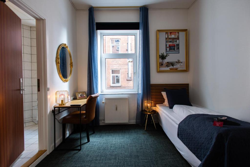 a bedroom with a bed and a desk and a window at Milling Hotel Ansgar in Odense