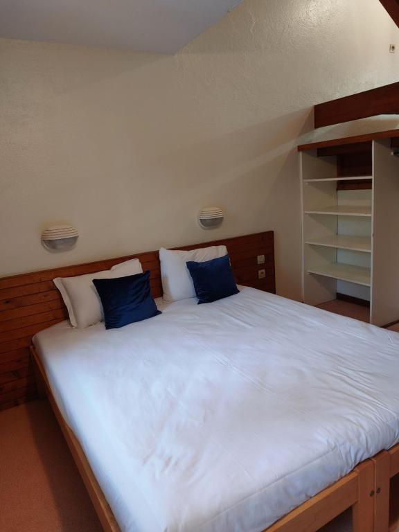 ein großes Bett mit zwei blauen Kissen darauf in der Unterkunft Résidence du Val de Villé in Albé