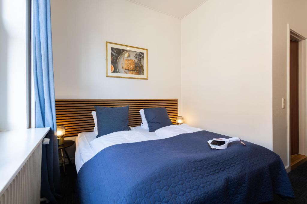 a bedroom with a blue and white bed with blue pillows at Milling Hotel Ansgar in Odense