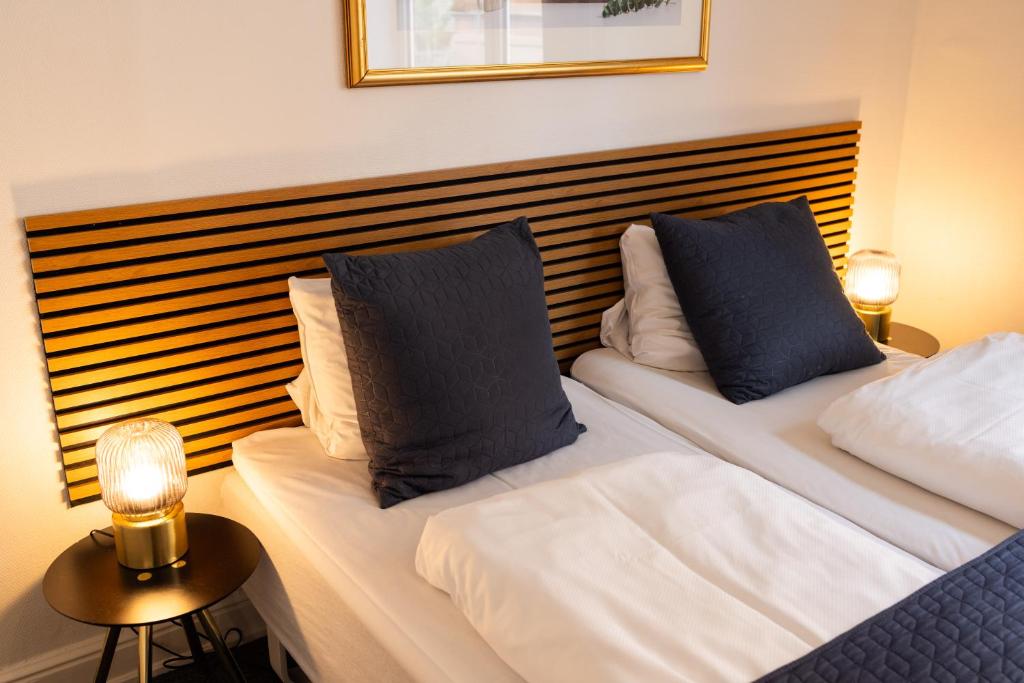 a bedroom with two beds with blue and white pillows at Milling Hotel Ansgar in Odense