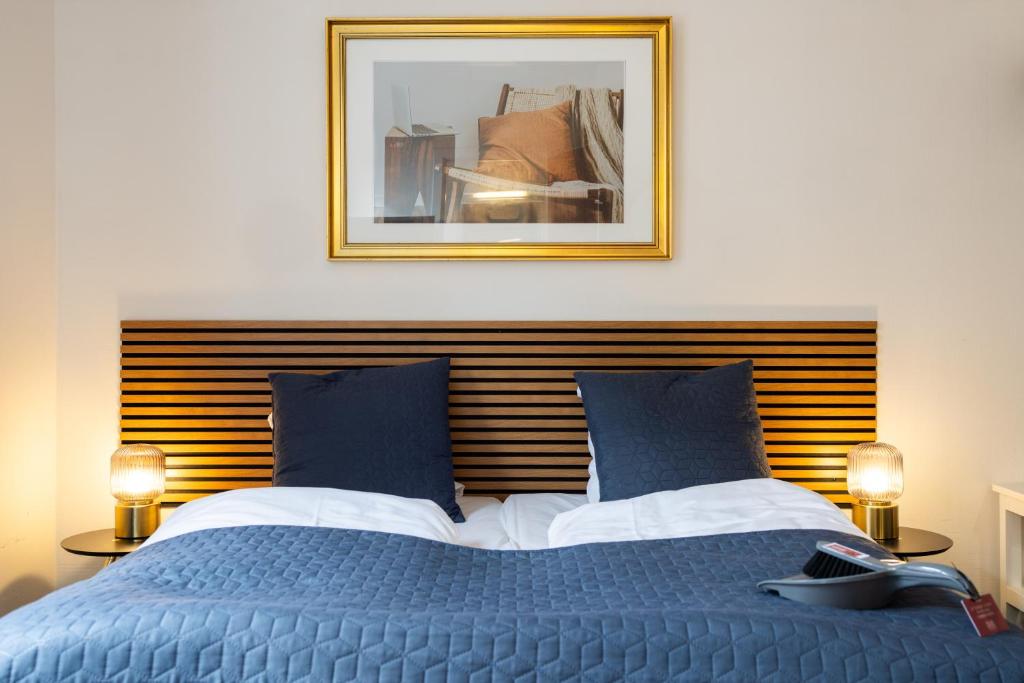 a bedroom with a blue bed with a picture on the wall at Milling Hotel Ansgar in Odense