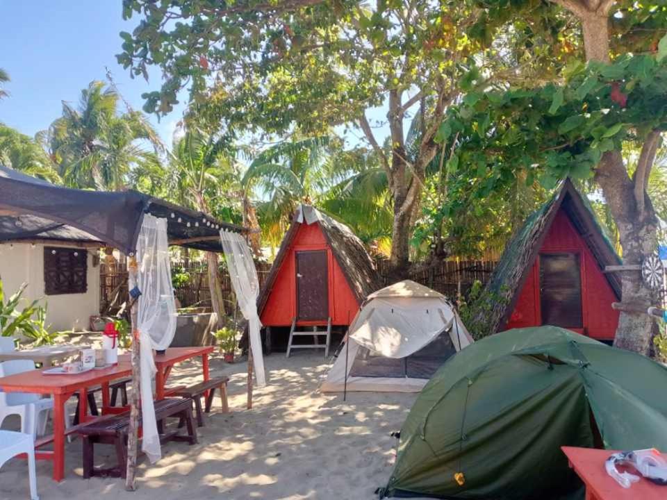 un gruppo di tende e tavoli nella sabbia sotto gli alberi di SHALOM CAMP a El Nido