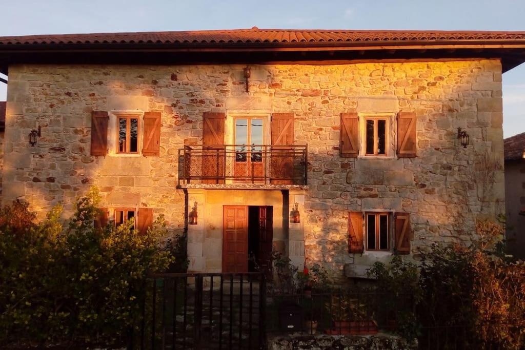 una vecchia casa in pietra con balcone sul lato anteriore di Kukuma Etxea Habitaciones con derecho a cocina a Galarreta