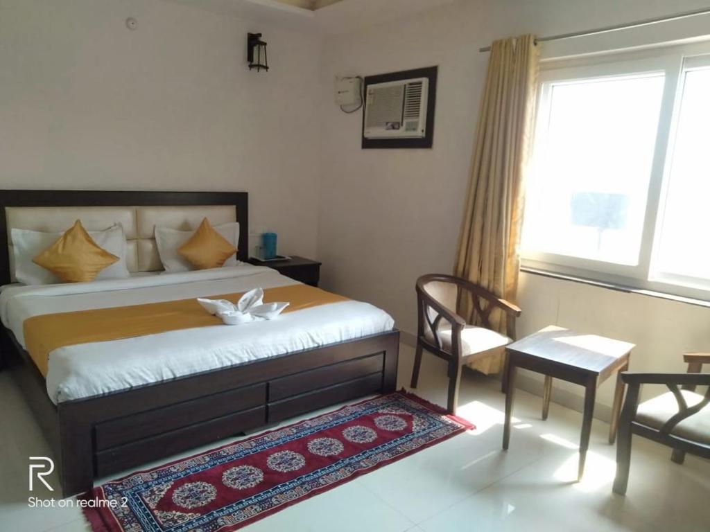 a bedroom with a bed and a chair and a window at Hotel Tulsi in Rishīkesh