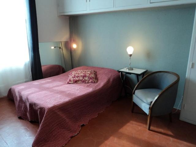um pequeno quarto com uma cama rosa e uma cadeira em Grande maison de vacances em Saint-Laurent-de-la-Salanque