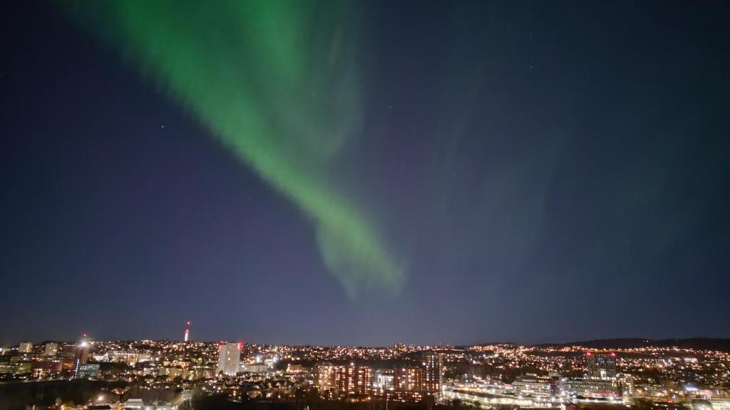 une image des lumières du nord dans le ciel au-dessus d'une ville dans l'établissement Adorable 1-bedroom apartment with a fantastic view - Free Parking, à Trondheim