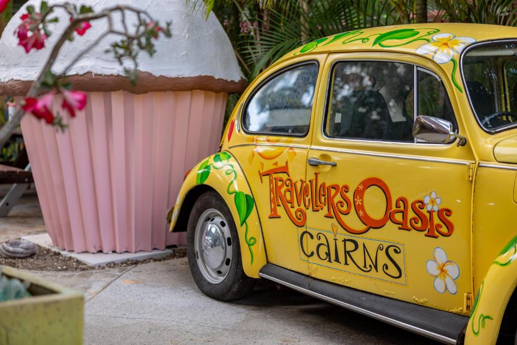 una piccola auto gialla parcheggiata accanto a un edificio di Travellers Oasis a Cairns