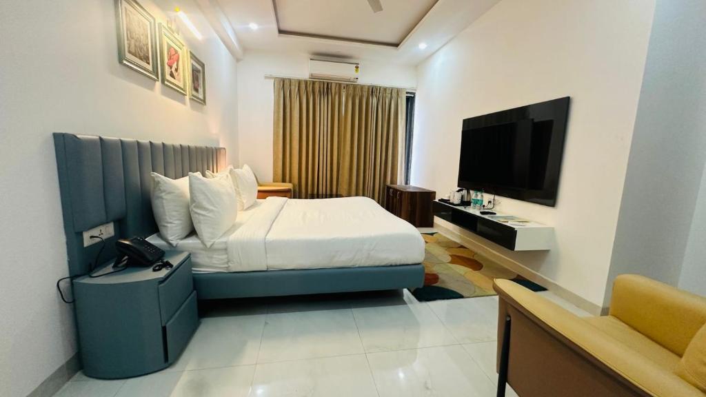 Habitación de hotel con cama y TV de pantalla plana. en Elite 32 Avenue - Near Google Building en Gurgaon