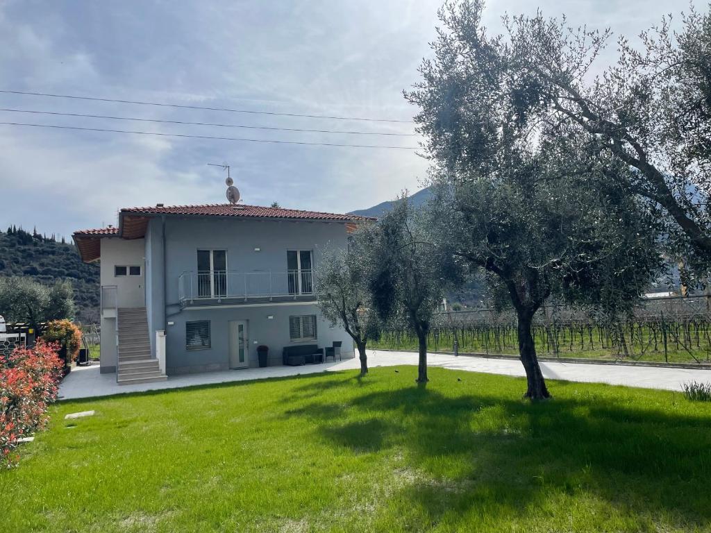uma pequena casa branca com um quintal com árvores em Lotus Garda em Riva del Garda