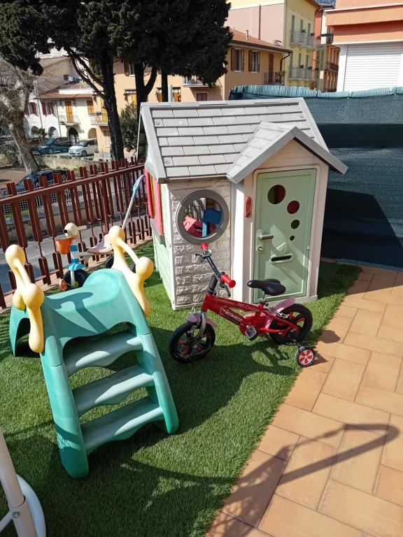 mały plac zabaw dla dzieci z domkiem zabawkowym i rowerem w obiekcie Garda City Home Family Apartments w mieście Garda