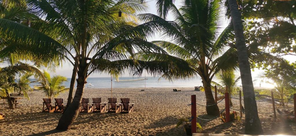 einen Strand mit Stühlen, Palmen und dem Meer in der Unterkunft Sulu Sunset Beach Resort in Nauhang