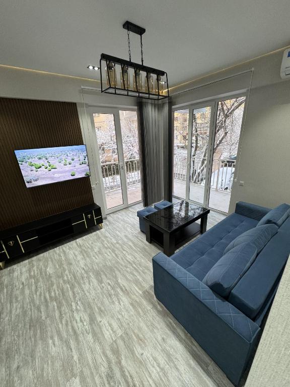New apartment in Yunusobod dist. في طشقند: غرفة معيشة مع أريكة زرقاء وتلفزيون بشاشة مسطحة