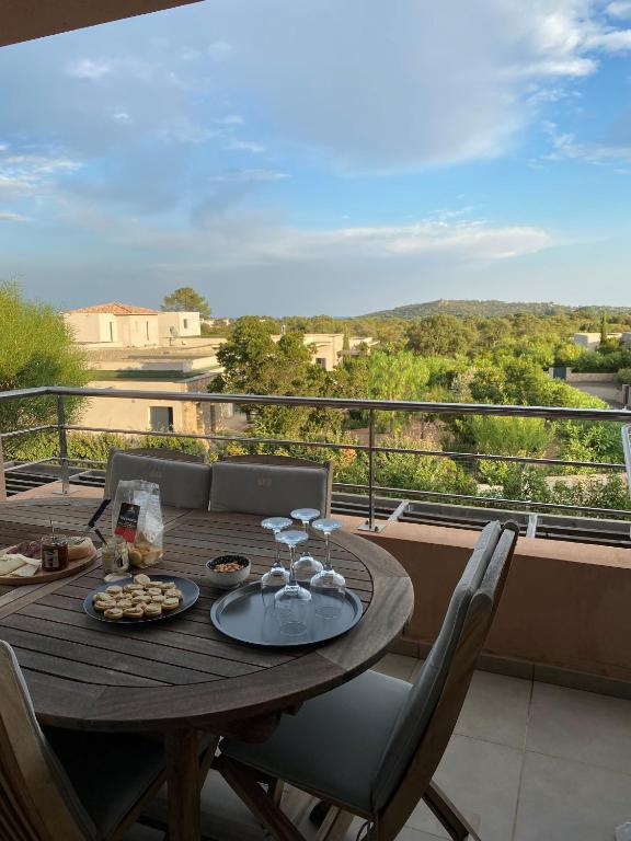 - une table en bois avec des verres à vin sur le balcon dans l'établissement Porto vecchio Résidence Don Andria T2, à Lecci
