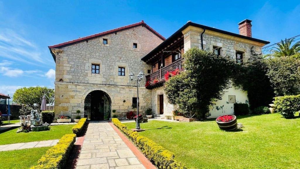 a large brick building with a gate in a yard at Posada La Victoria in Miengo