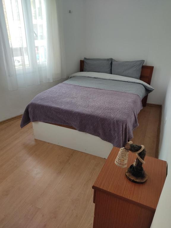 1 dormitorio con 1 cama con manta morada y mesa en Arya en Ayvalık