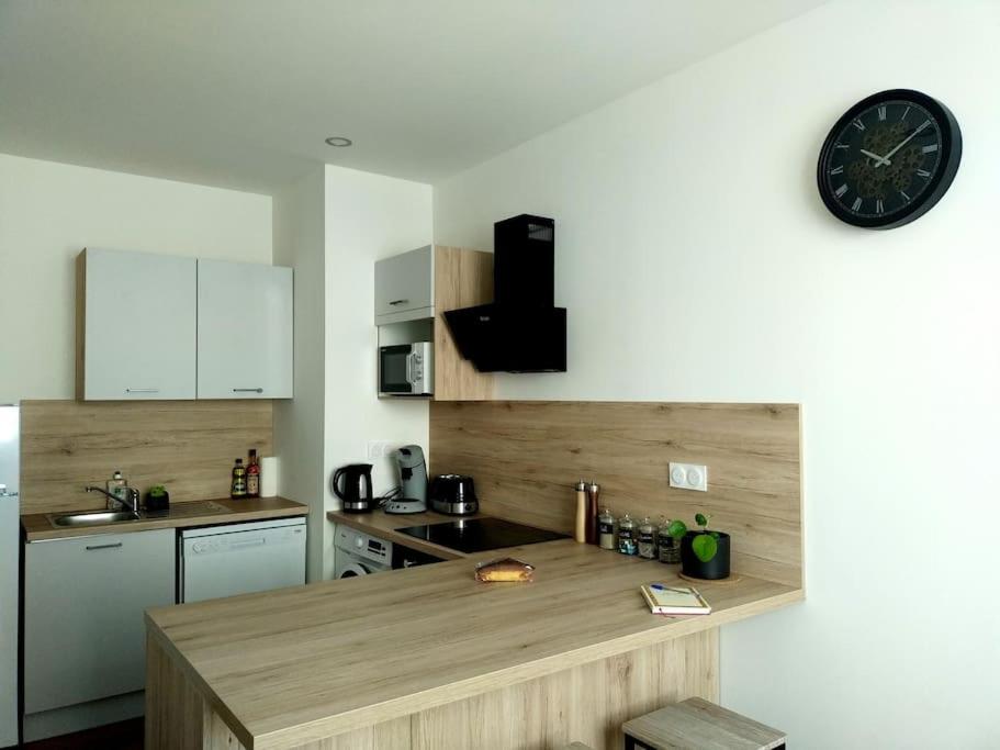une cuisine avec un comptoir et une horloge au mur dans l'établissement Appartement proche centre-ville, à Langogne