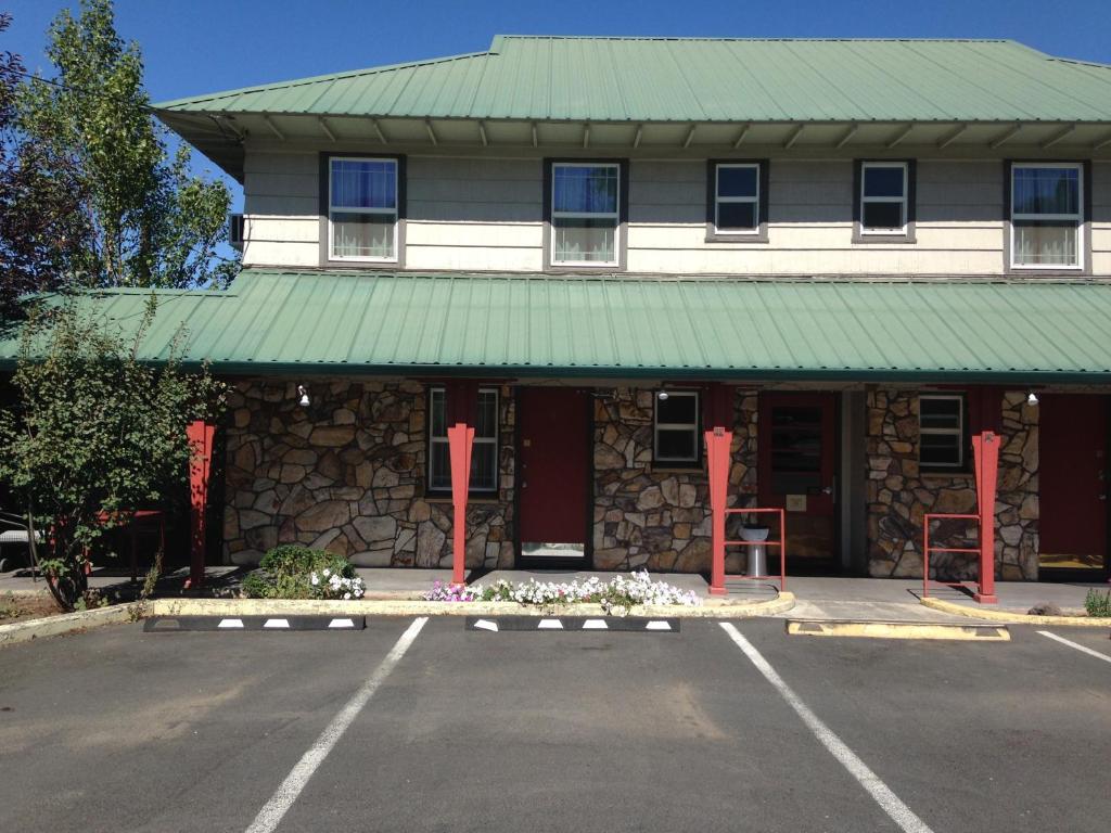 a building with a green roof and a parking lot at Rugged Country Lodge in Pendleton
