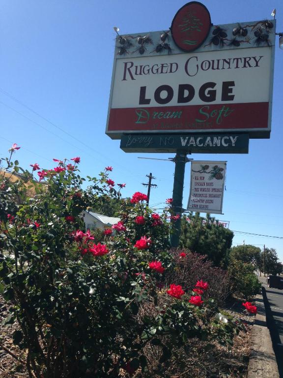 a sign for a riegued country lodge with flowers at Rugged Country Lodge in Pendleton