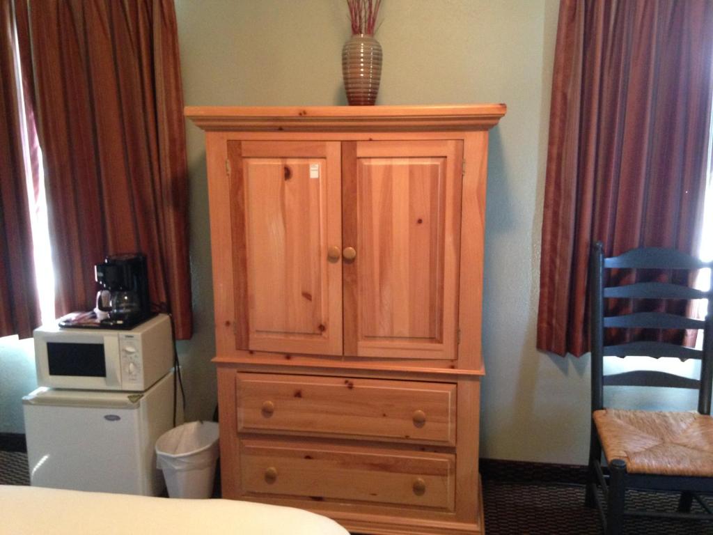 a wooden cabinet in a room with a microwave at Rugged Country Lodge in Pendleton