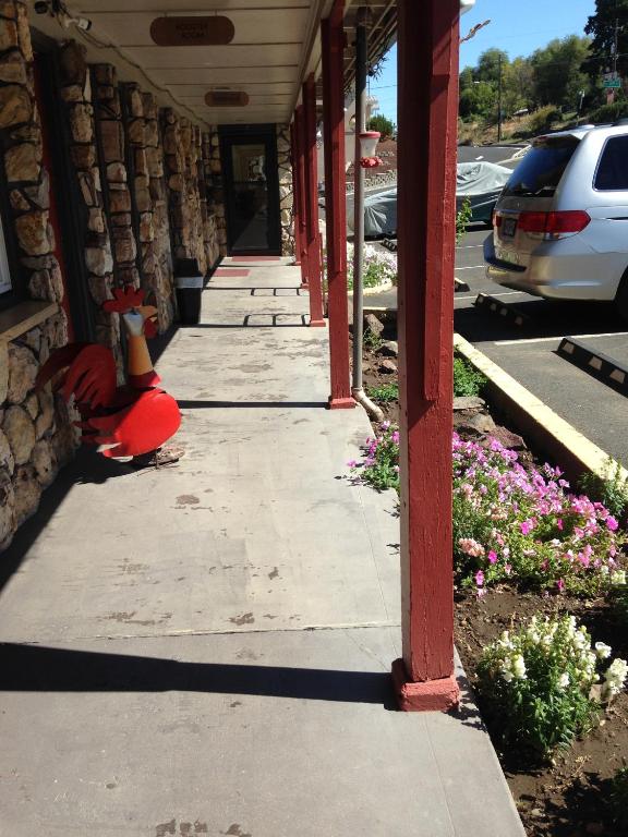 a red building with a bird sitting on a sidewalk at Rugged Country Lodge in Pendleton