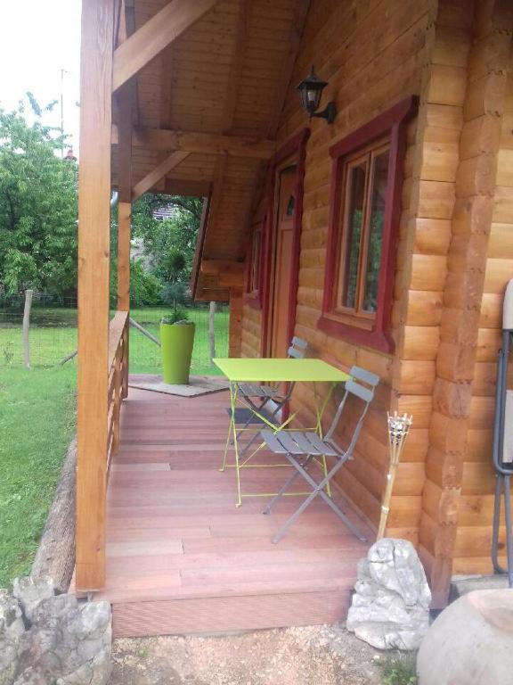 une véranda d'une cabane en rondins avec une table et des chaises dans l'établissement Le petit chalet jurassien, à Jouhe
