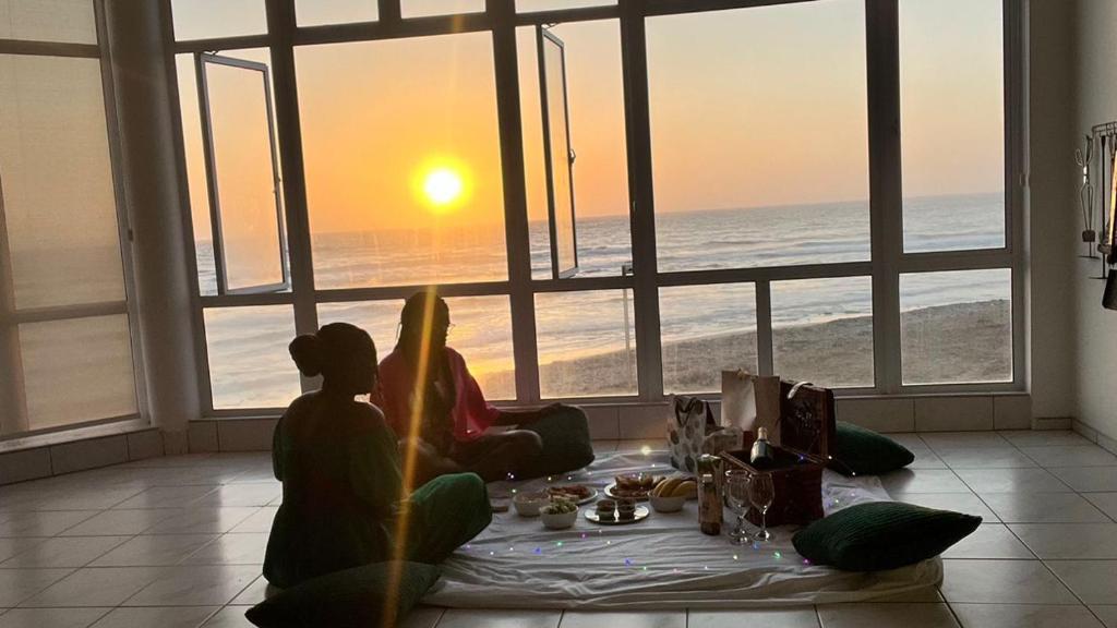 Due persone sedute su un tavolo che guardano l'oceano di Camere da Letto ON-THE-BEACH Self Catering a Swakopmund
